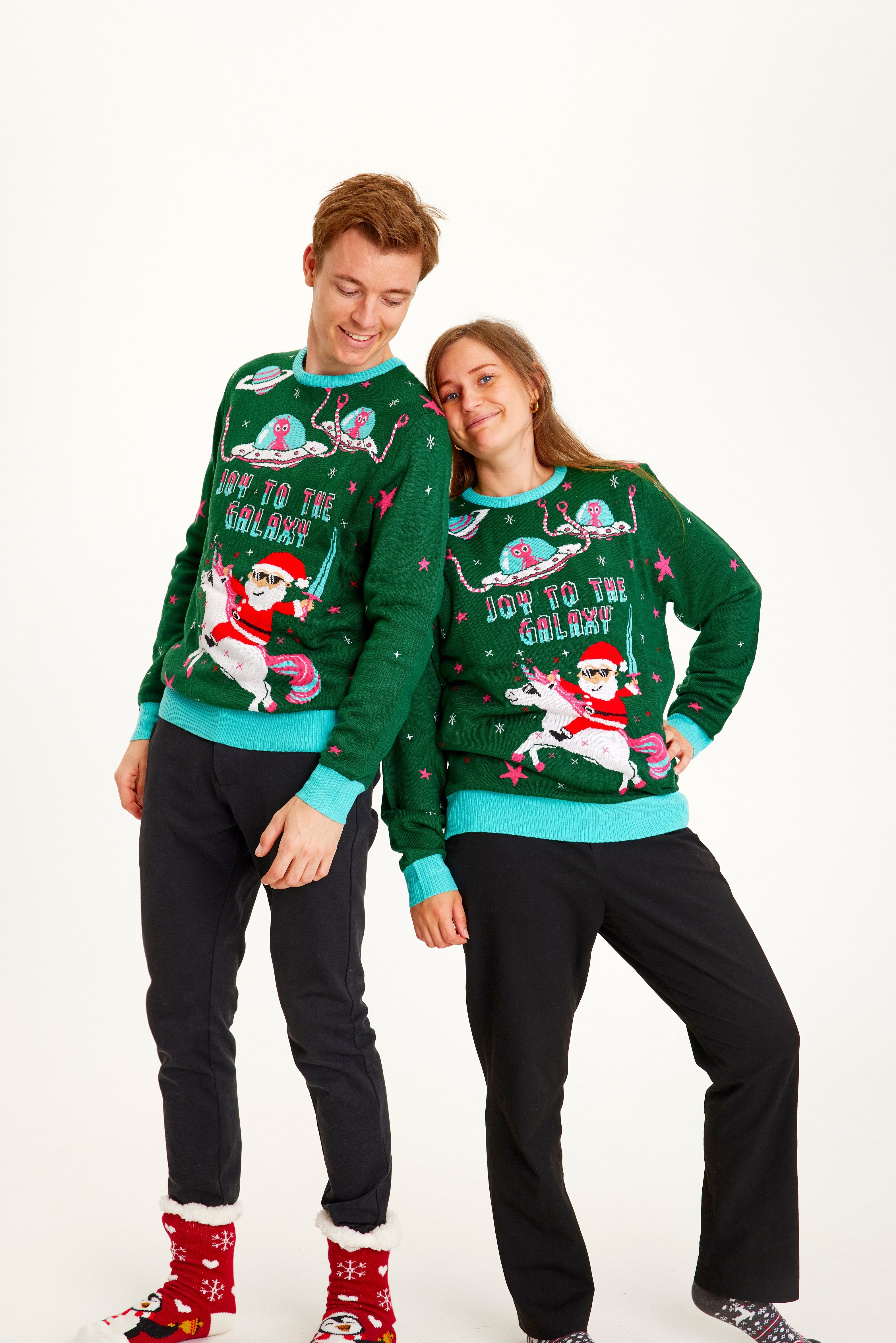 En mand og en kvinde poserer i deres grønne julesweatre.
